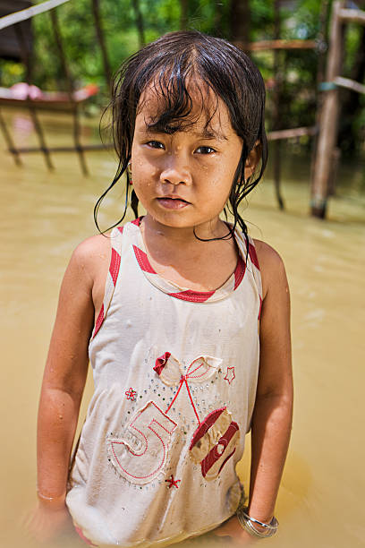 bambina divertendosi nell'acqua durante l'inondazione, cambogia - flood people asia cambodia foto e immagini stock