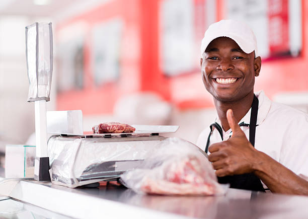 Butcher with thumbs up Portrait of a male butcher weighting a cut of meat looking very happy market vendor stock pictures, royalty-free photos & images