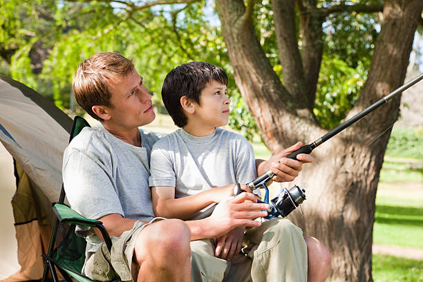 istock Father and son fishing while sitting next to their tent 451994927