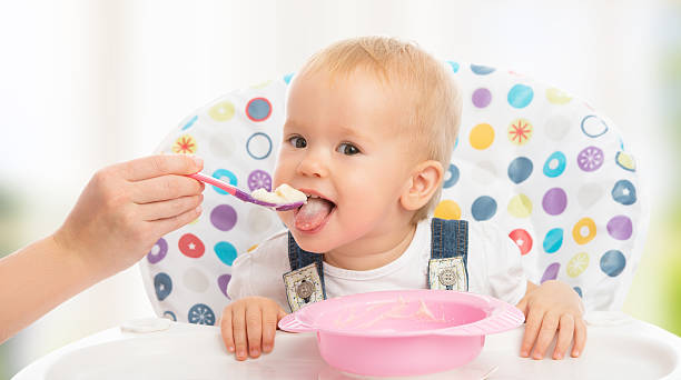 happy mother feeds funny  baby from  spoon
