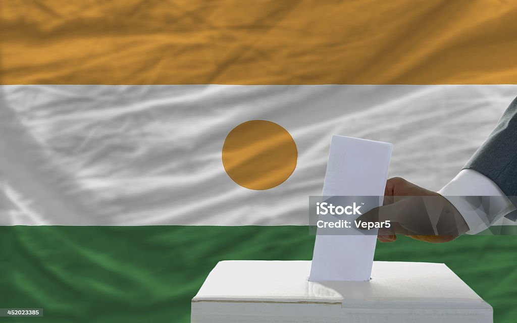 Homme de voter sur les élections en face du drapeau de la République du niger - Photo de Adulte libre de droits