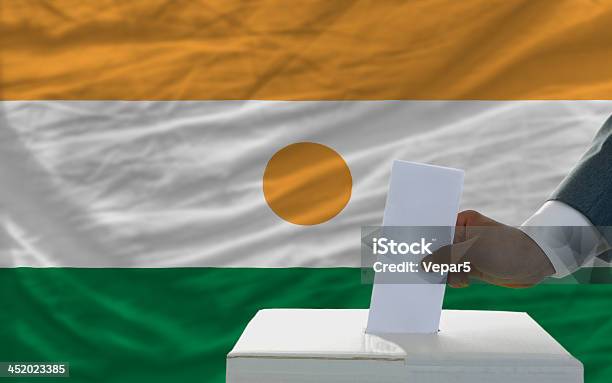 Photo libre de droit de Homme De Voter Sur Les Élections En Face Du Drapeau De La République Du Niger banque d'images et plus d'images libres de droit de Adulte