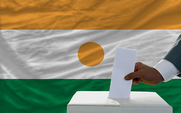 istock man voting on elections in front flag of niger 452023385