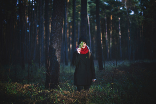 Young woman in the dark forest. Hipster portrait