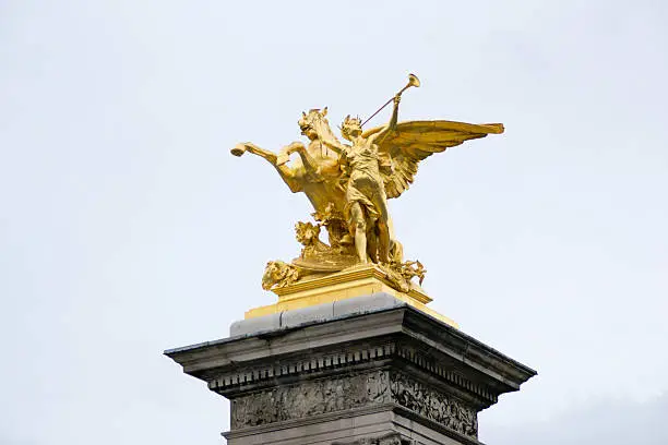This golden statue is located on the Pont Alexandre III, an arch bridge that spans the Seine, connecting the Champs-Élysées quarter and the Invalides and Eiffel Tower quarter, widely regarded as the most ornate, extravagant bridge in Paris
