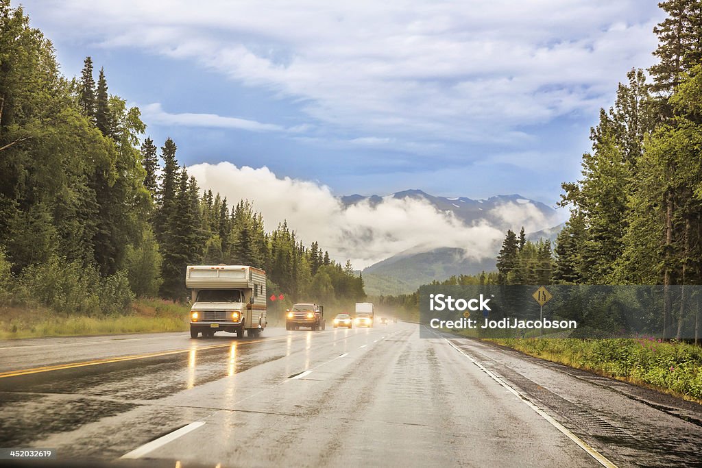 Vehicles driving on a scenic highway in the rain Various types of vehicles are driving on a scenic multi lane highway in the rain.  All of the vehicles are driving in the same direction.  rr Motor Home Stock Photo