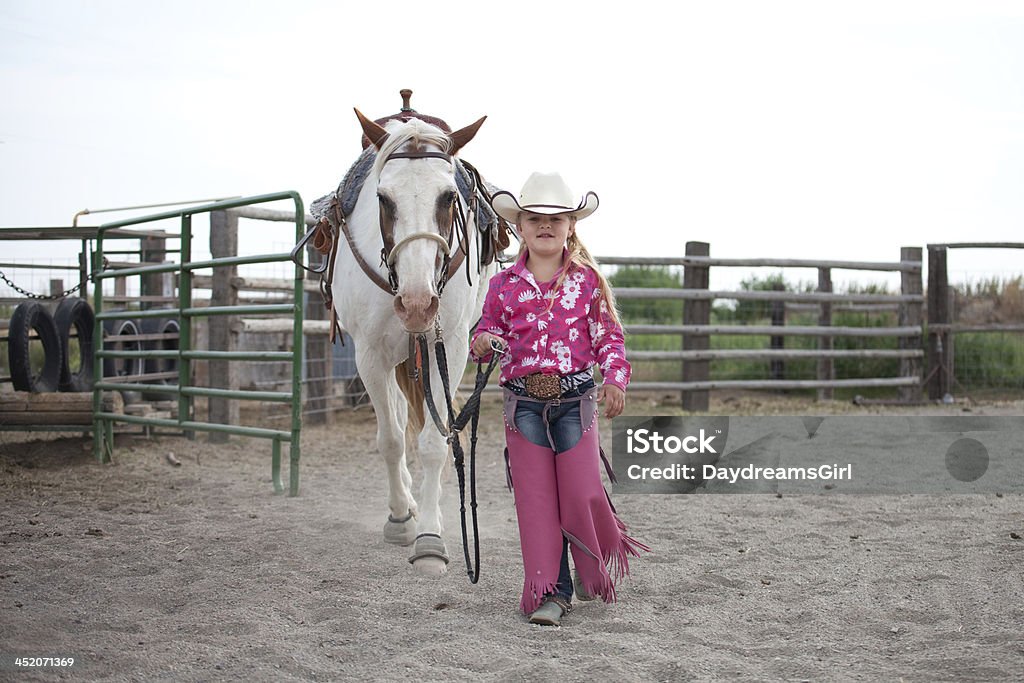 Little Cowgirl Walking with Horse Little cowgirl wearing pink and walking horse. Horse Stock Photo