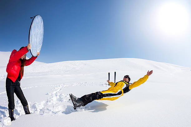 Assistant girl holding reflector to skier