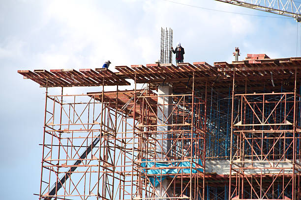 istock Crane and workers at construction site against blue sky. Thailand 452074149
