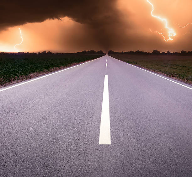 istock Driving on an empty road towards tornado and lightning 452081121