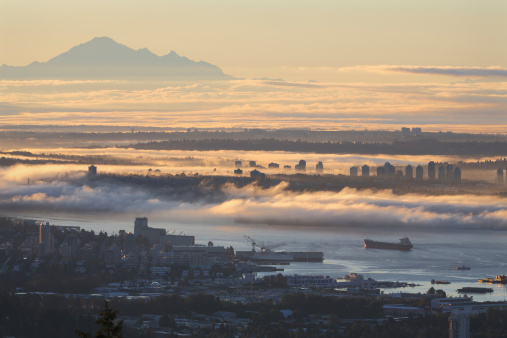 A high angle view of Vancouver and the Burrard Inlet at sunrise. Mount Baker, in Washington State, rises in the distance. British Columbia, Canada.