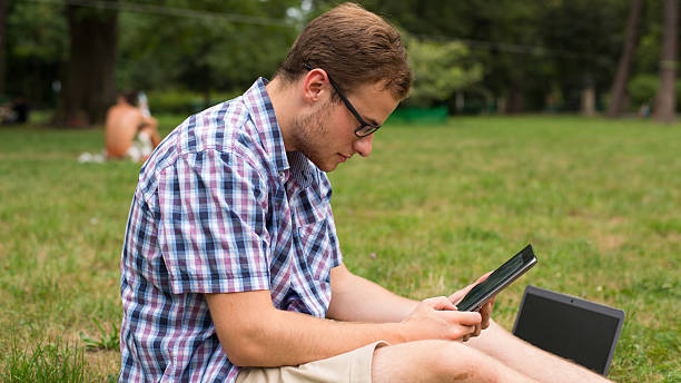 istock Student at the park with tablet sitting on a grass. 452086191
