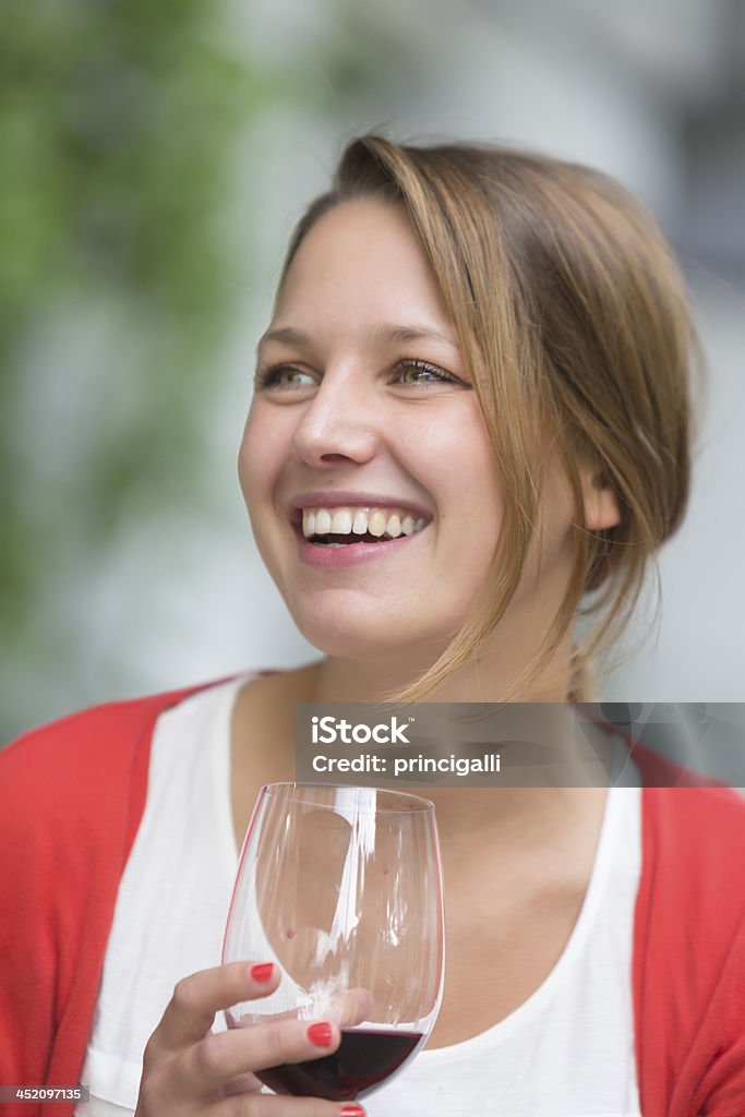 Happy woman with glass red wine. Cheerful young woman holding a glass of red wine outdoors. 20-29 Years Stock Photo