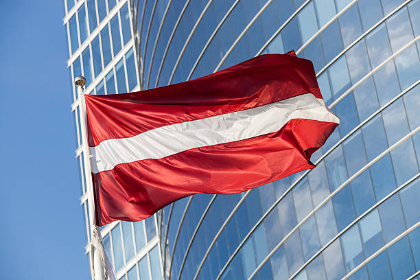 drapeau letton contre les gratte-ciel de riga - latvia flag photos et images de collection