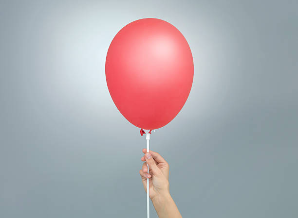 istock female hand holding a red balloon 452124071