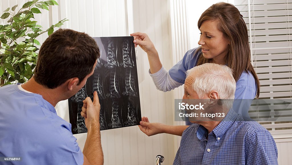 Healthcare: Nurse and doctor review x-ray with disabled patient. Doctor and nurse or therapists review x-rays with disabled patient at doctor's office or home. Doctor Stock Photo