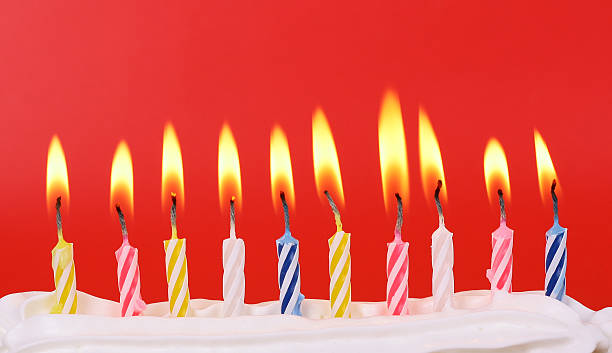 Row of ten colorful birthday candles lit on a red background ten lit birthday candles in bright colors with red background  10 11 years photos stock pictures, royalty-free photos & images