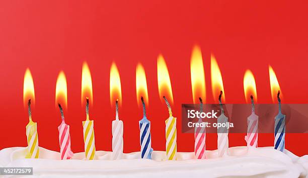 Row Of Ten Colorful Birthday Candles Lit On A Red Background Stock Photo - Download Image Now