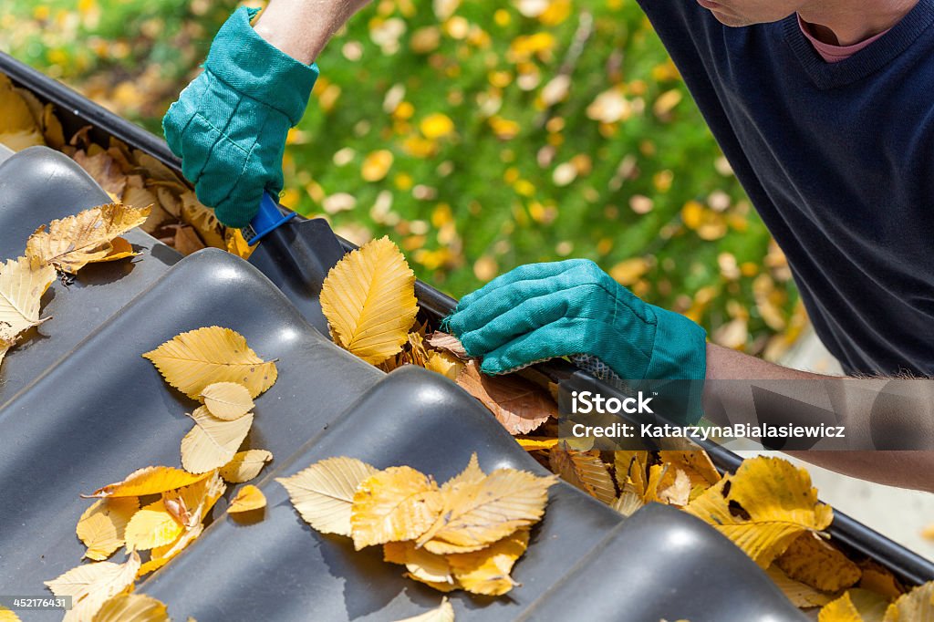 Man cleaning the gutter Man cleaning the gutter from autumn leaves Roof Gutter Stock Photo