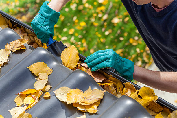 Man cleaning the gutter Man cleaning the gutter from autumn leaves roof gutter photos stock pictures, royalty-free photos & images