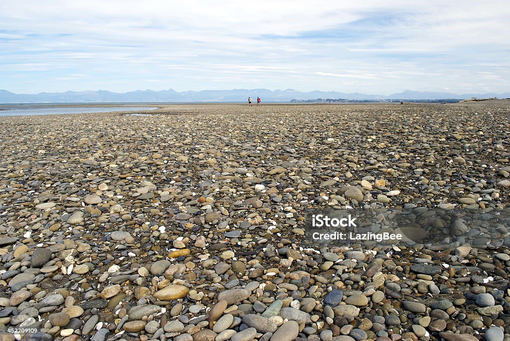 Stoney spiaggia con molto distante Walkers - Foto stock royalty-free di Angolatura insolita