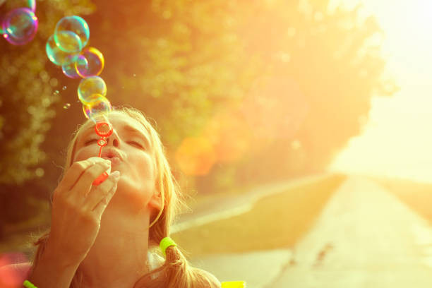 Young woman having fun and blowing bubbles outdoors stock photo