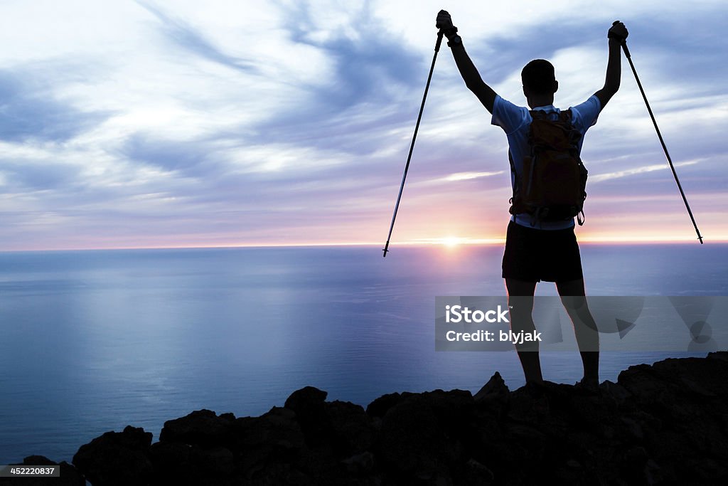 silhouette uomo escursioni in montagne, oceano e del tramonto - Foto stock royalty-free di Braccia tese