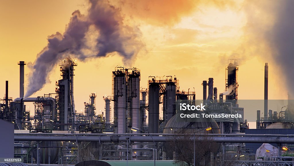 Smokestack in factory Smokestack in factory with yellow sky and clouds Oil Refinery Stock Photo