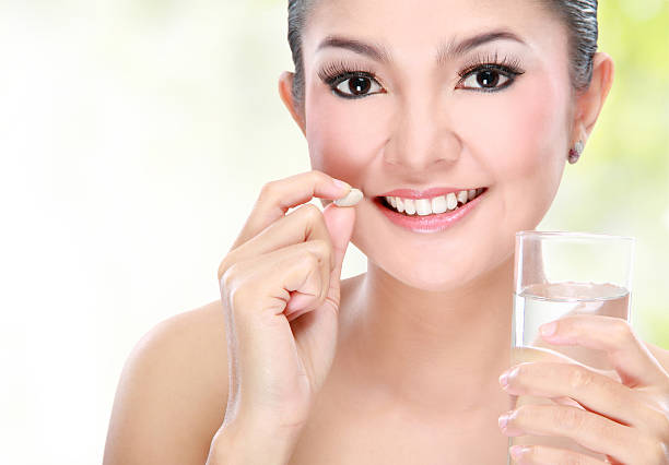 istock woman taking vitamin tablet 452246407