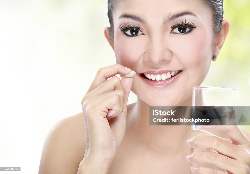 woman taking vitamin tablet Portrait of a beautiful asian young woman taking vitamin tablet Adult Stock Photo