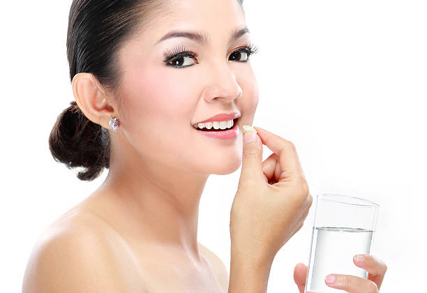 istock woman taking vitamin tablet 452246499