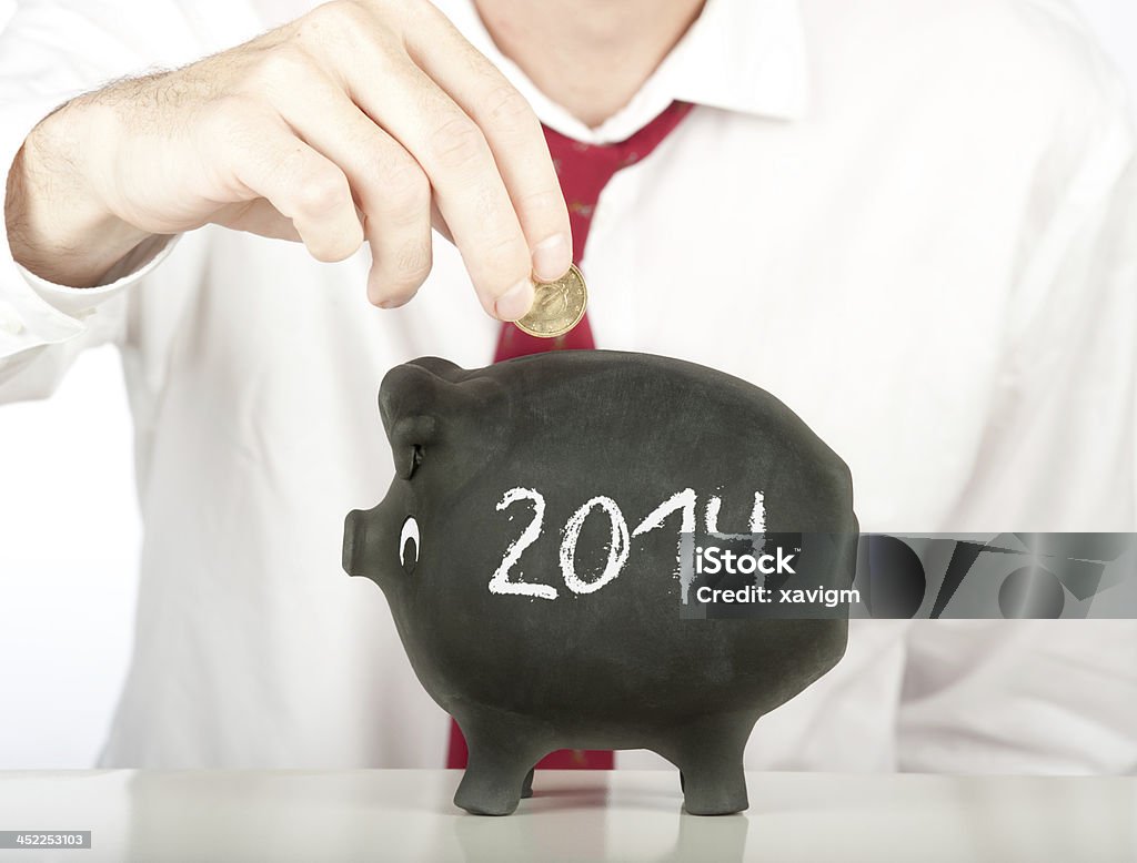 businessman putting money on a 2014 piggy bank businessman putting money on a piggy bank with a year 2014 drawing 2014 Stock Photo