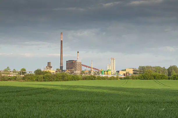 Poland, Zabrze, Biskupice coking plant seen over green field, spring