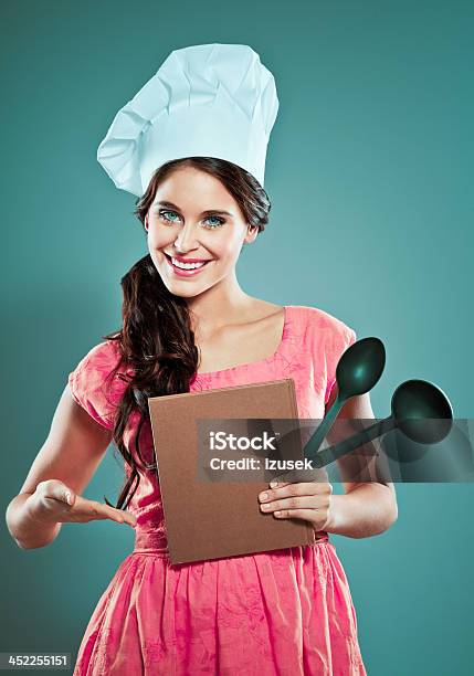 Mujer Joven Usando Gorro De Chef Foto de stock y más banco de imágenes de Libro de cocina - Libro de cocina, Exhibir, Agarrar