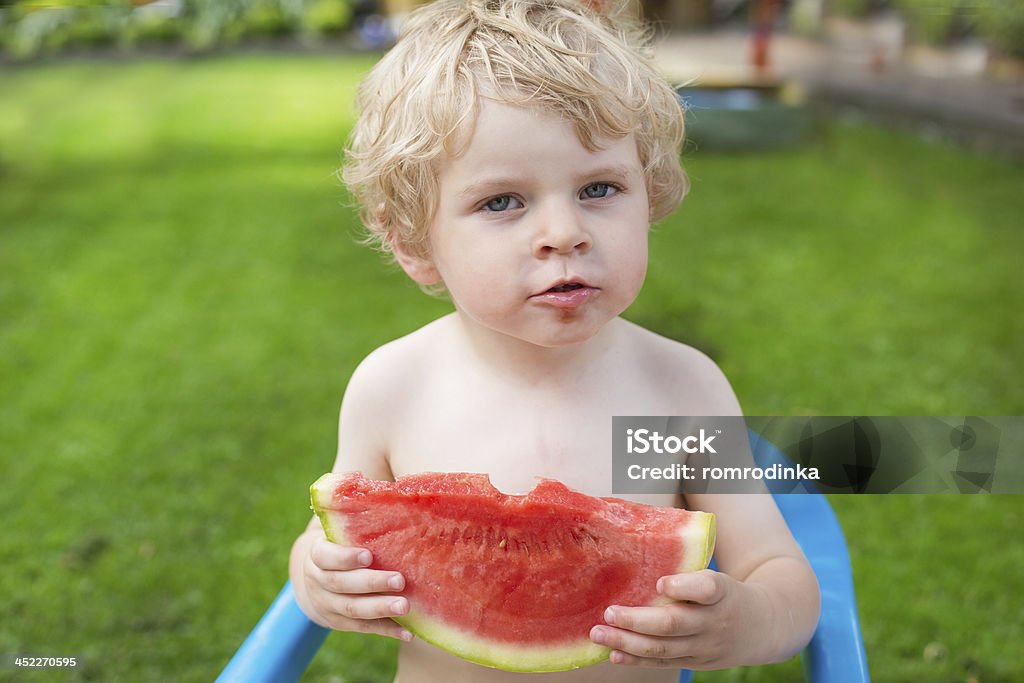 Adorabile piccolo ragazzo bambino con i capelli biondi capelli mangiare anguria - Foto stock royalty-free di 2-3 anni