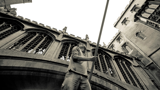 Lazy Sunday afternoon on the River Cam in Cambridge, England, Good looking young man punting underneath a University stone bridge.