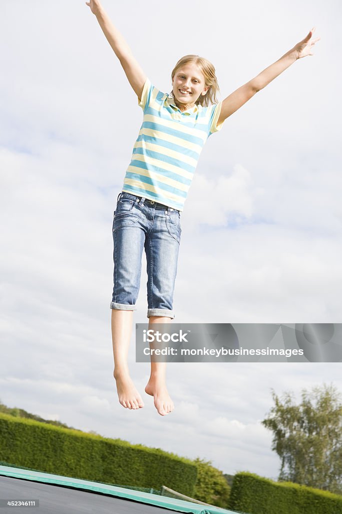 Giovane ragazza saltando sul trampolino sorridente - Foto stock royalty-free di Allegro