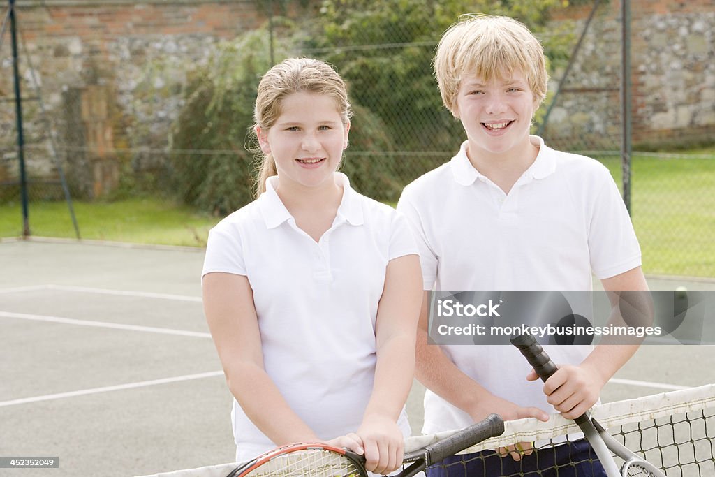 Два молодых друзей с ракетки на теннисный корт, улыбается - Стоковые фото Активный образ жизни роялти-фри