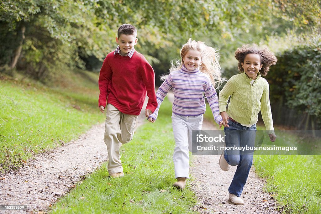 Trzech młodych przyjaciół na ścieżkę na zewnątrz biegania uśmiech - Zbiór zdjęć royalty-free (Biegać)
