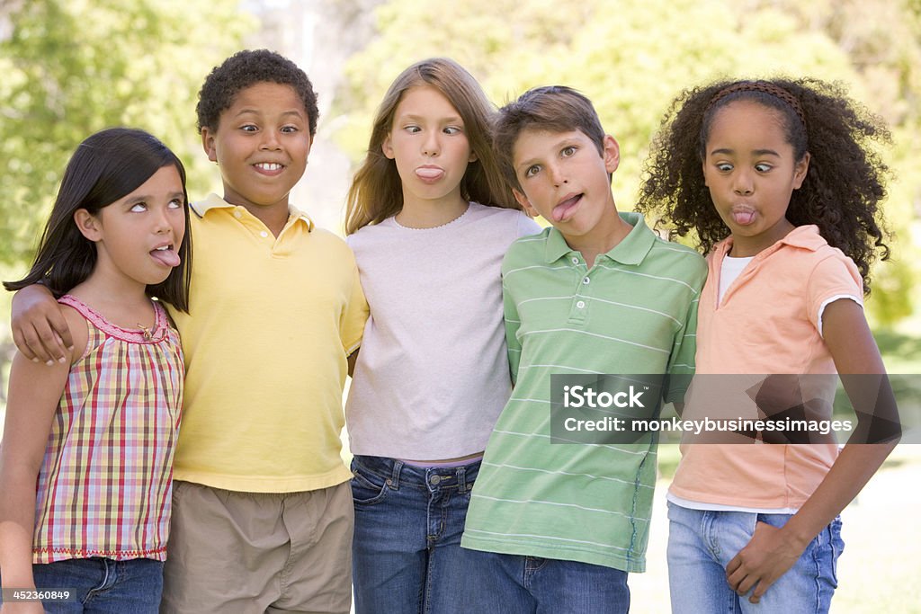 Pięć młodych przyjaciół, stojący na zewnątrz co Śmieszne twarze - Zbiór zdjęć royalty-free (Dziecko)