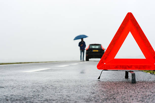 car with a breakdown in the rain and fog man with an umbrella besides his broken car alongside a road in the middle of nowhere vehicle breakdown stock pictures, royalty-free photos & images