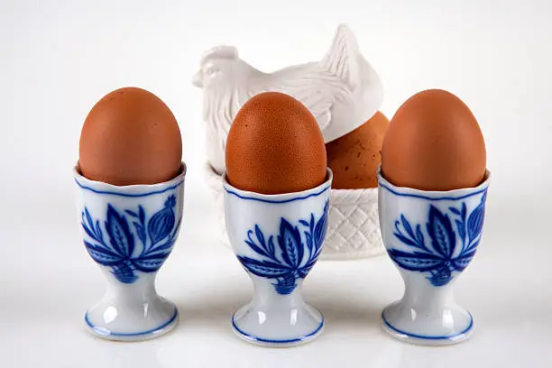 Hen egg in a blue eggcup on a white background