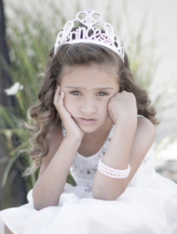 A little girl is bored and dressed as a princess