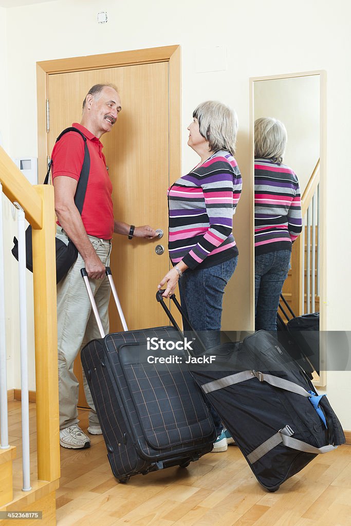 Pareja madura con las maletas cerca de puerta - Foto de stock de 50-59 años libre de derechos