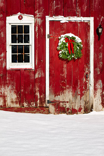 couronne de noël verte avec de la neige fraiche porte de grange - barn red old door photos et images de collection