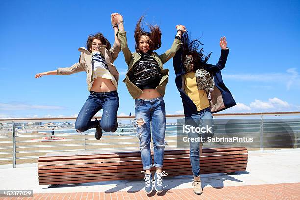 Foto de Alegre Adolescentes Jumping e mais fotos de stock de 18-19 Anos - 18-19 Anos, Abraçar, Adolescente