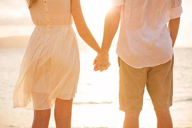 istock Couple holding hands at sunset on beach 452463195