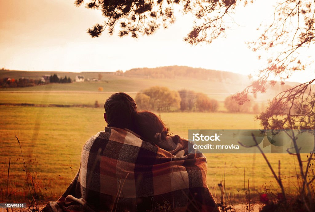 Enjoying the view together Young couple sitting back having covered with coverlet and enjoy the scenery on the edge of the forest Autumn Stock Photo