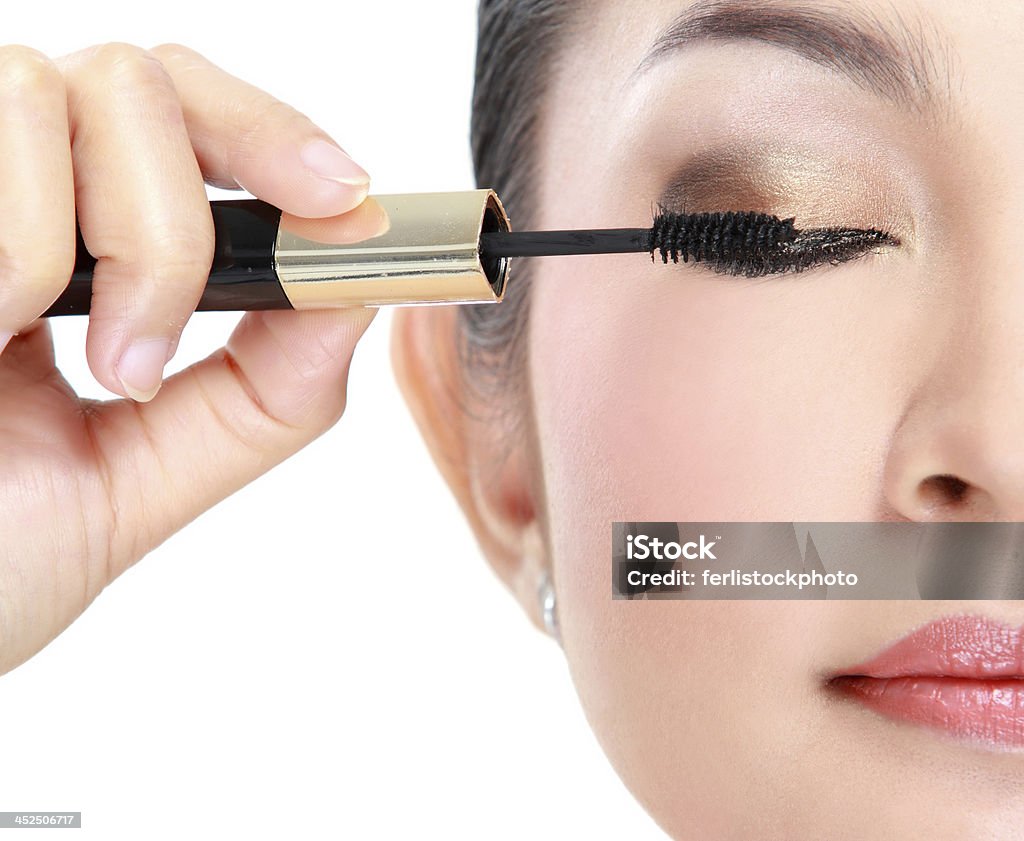 Woman with mascara Beautiful woman applying mascara on her eyelashes isolated on white background Adult Stock Photo