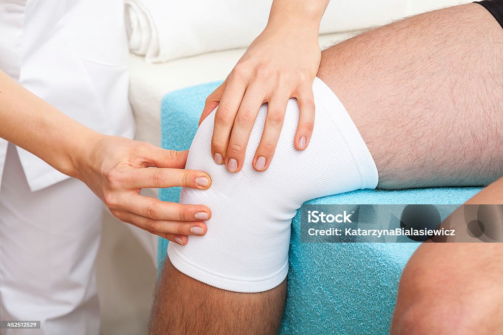 Examination of knee Doctor examining the twisted knee of patient Adhesive Bandage Stock Photo